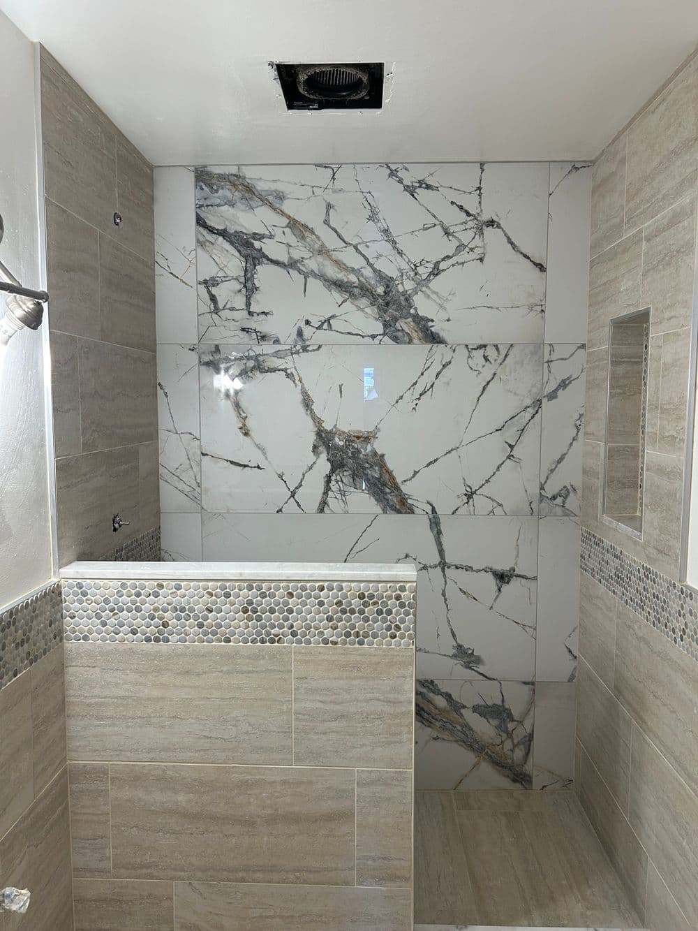 Modern bathroom shower featuring elegant marble walls and stylish stone accents.