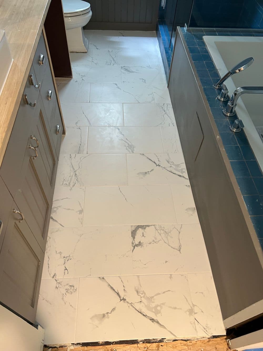 Modern bathroom with marble tile floor, blue sink, and stylish cabinetry.