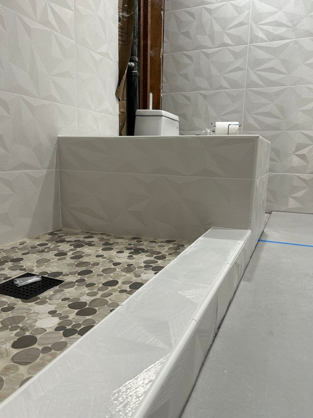 Modern bathroom design featuring textured tiles, a walk-in shower, and a sleek toilet setup.